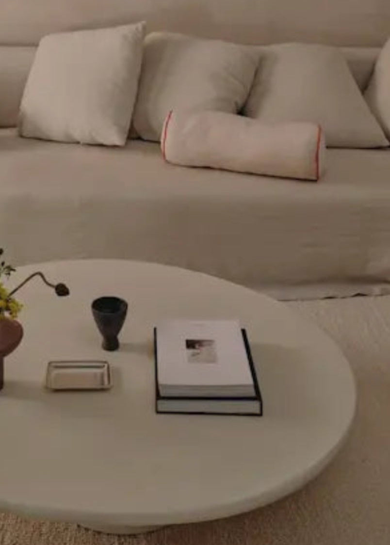 Living room with a beige sofa, round coffee table, and wooden chairs.